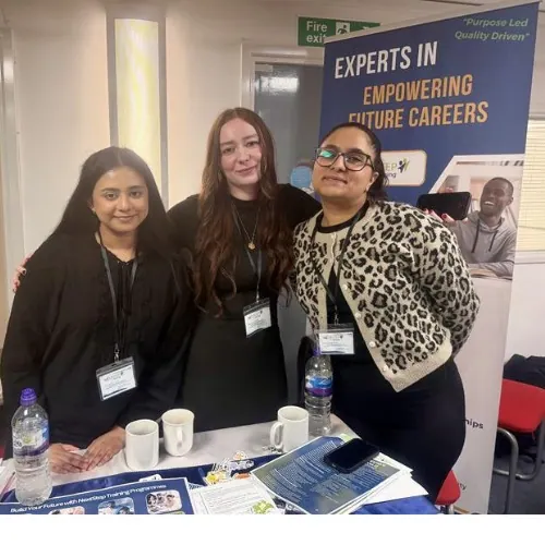 Three team members stand behind the NextStep careers-fair table.