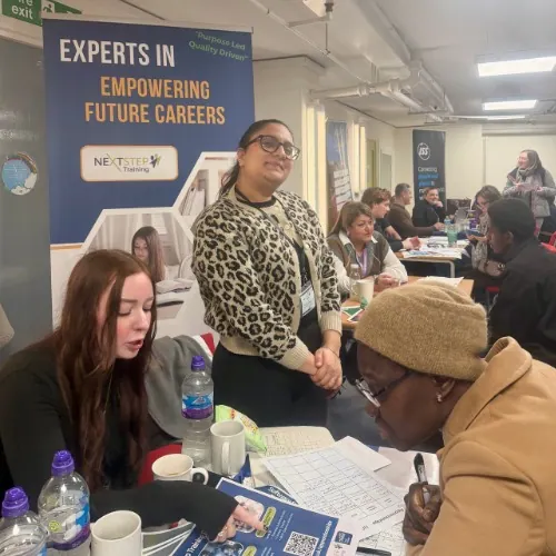 Team members help a visitor with paperwork at the careers-fair stand.