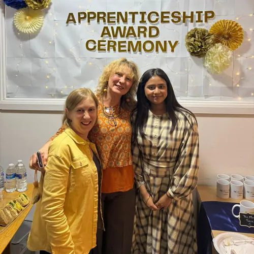 Three people pose together beside the Apprenticeship Award Ceremony banner.