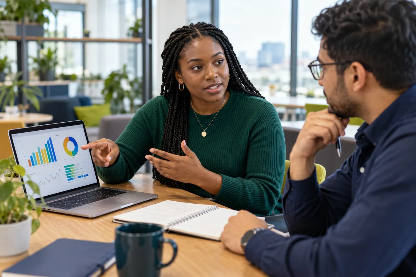 A data analyst explaining a dashboard to a colleague at a meeting table.