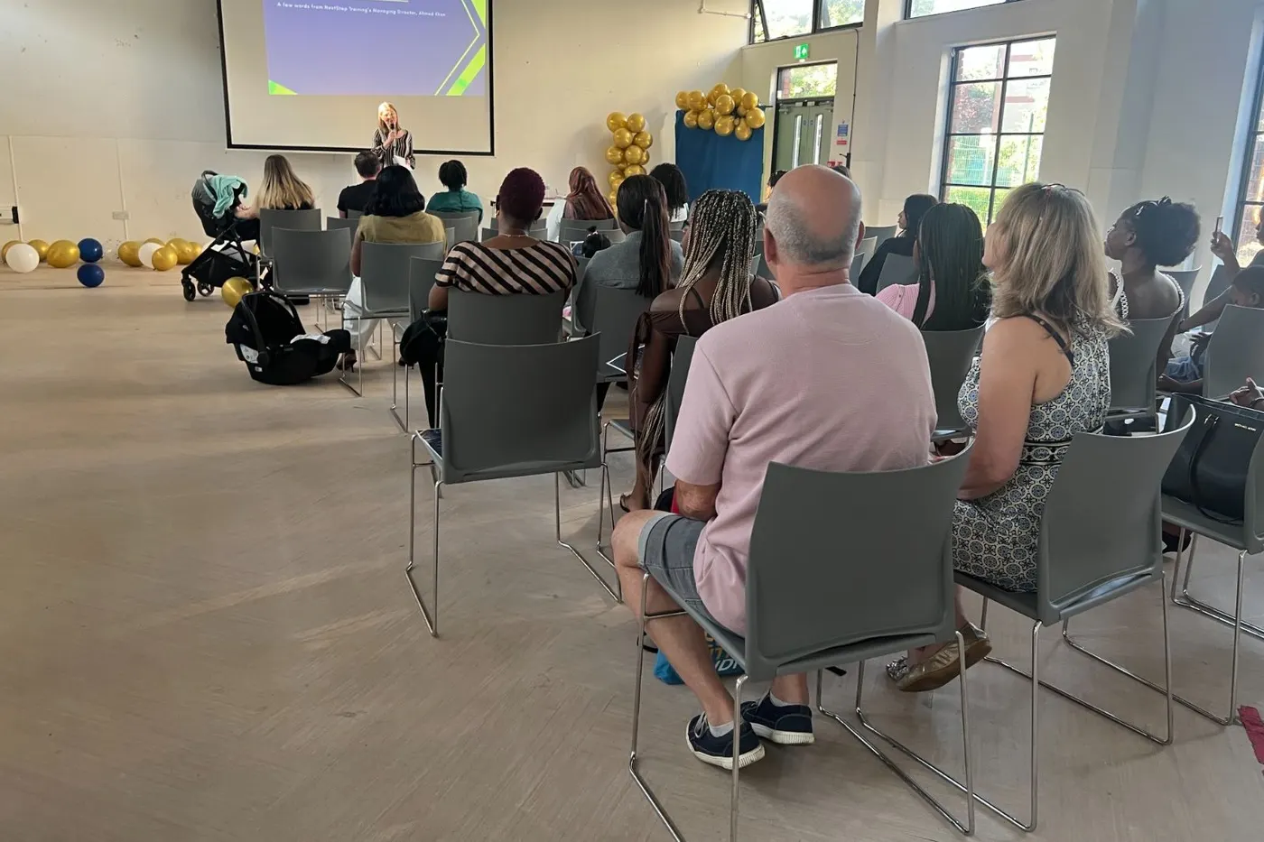 Guests seated in rows listening to a speaker at a NextStep graduation event.