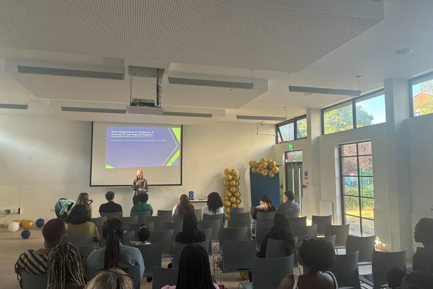 A speaker addressing graduates and guests at a NextStep graduation event.